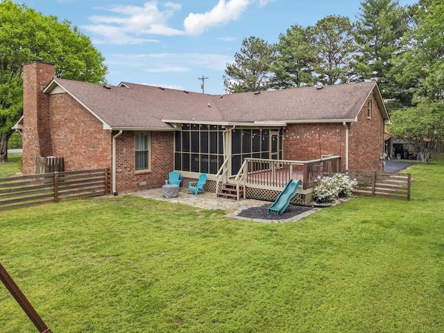 rear view of house featuring a chimney, a sunroom, brick siding, and roof with shingles