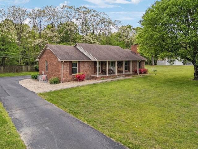 ranch-style home with a front lawn, a porch, a chimney, fence, and brick siding