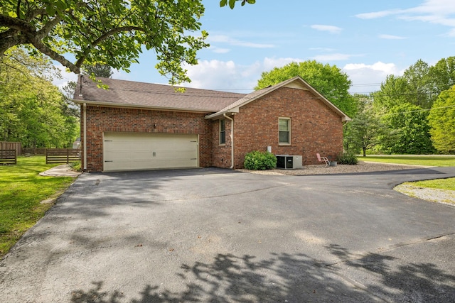 view of front of property featuring a front lawn, driveway, fence, cooling unit, and brick siding