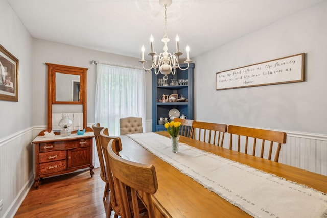 dining space with wood finished floors, a wainscoted wall, and a chandelier