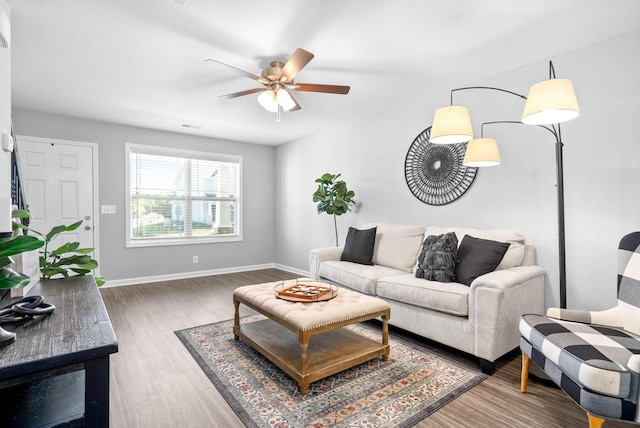 living room featuring baseboards, wood finished floors, and ceiling fan