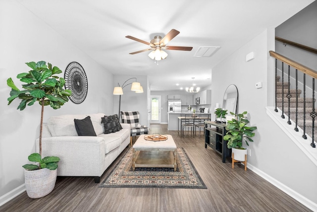 living room featuring dark wood-style floors, visible vents, baseboards, stairs, and ceiling fan with notable chandelier