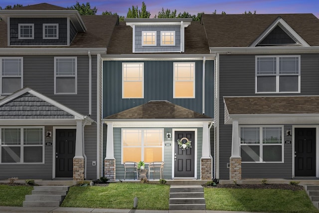 townhome / multi-family property featuring board and batten siding, roof with shingles, and stone siding