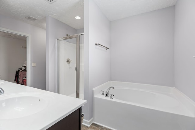 bathroom featuring double vanity, visible vents, a sink, a bath, and a stall shower