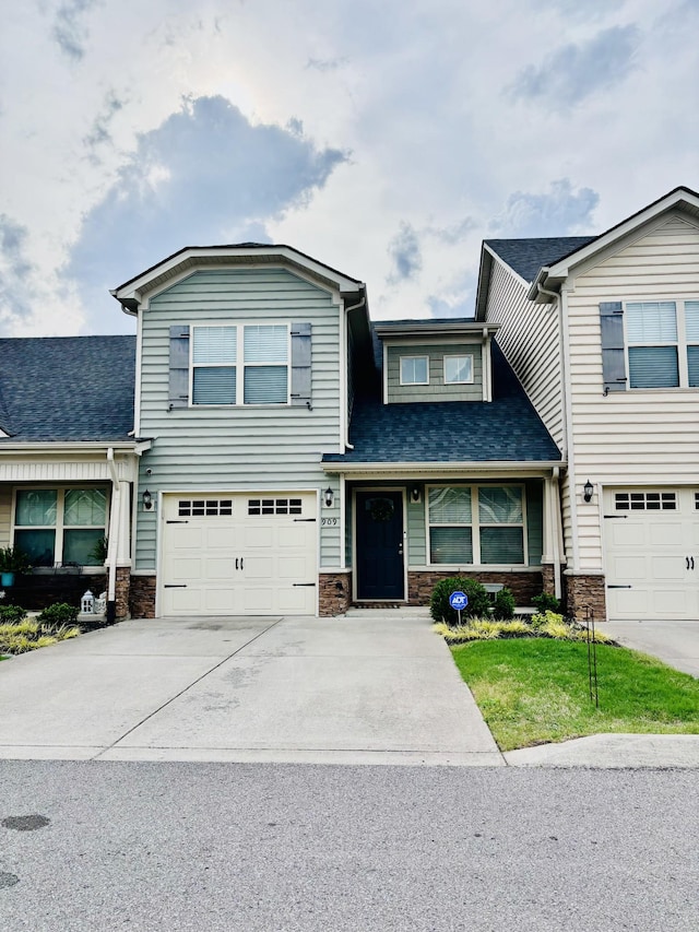 view of front of property featuring an attached garage, driveway, stone siding, and a shingled roof