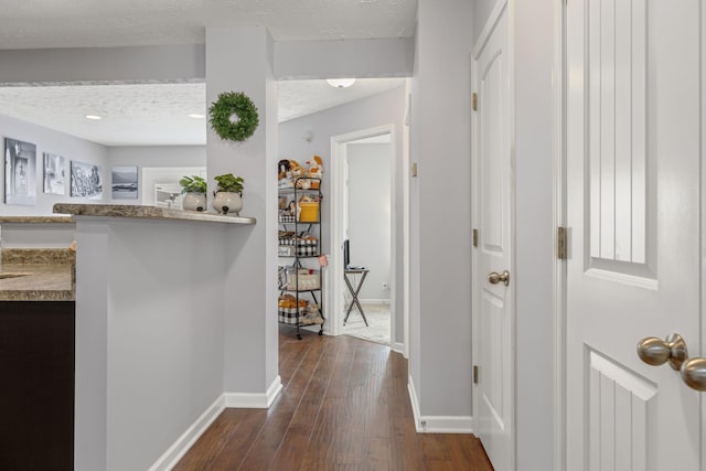 corridor featuring baseboards, a textured ceiling, and dark wood finished floors