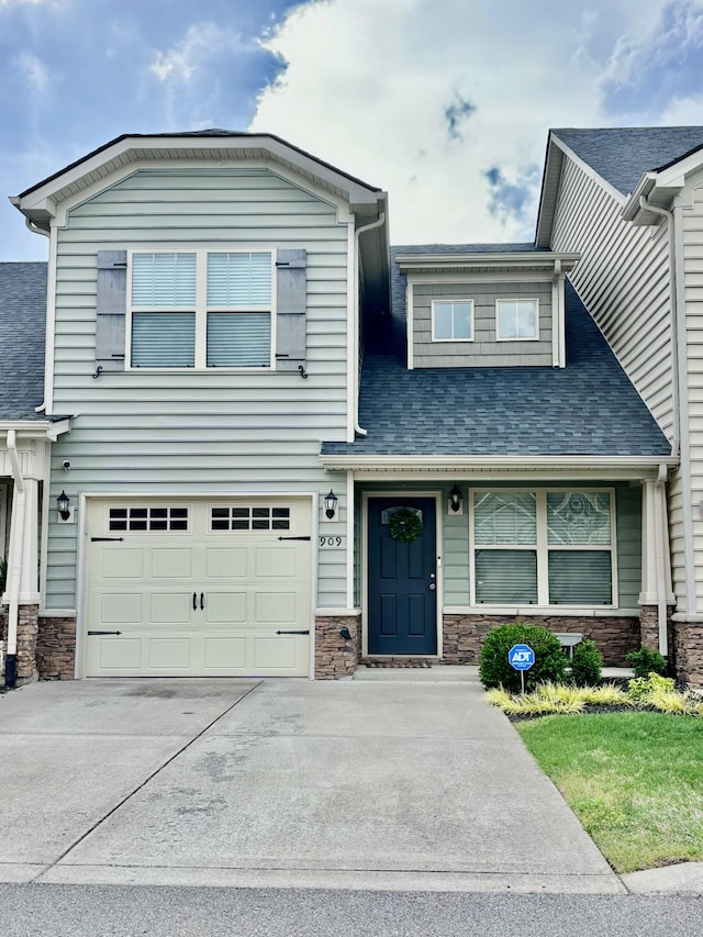 view of front of property with stone siding, an attached garage, driveway, and roof with shingles