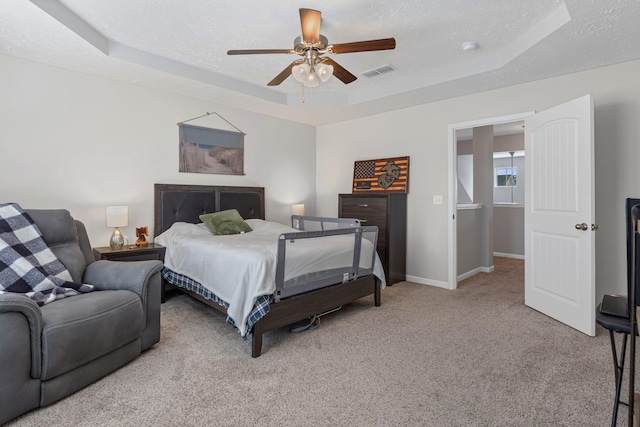 carpeted bedroom with a raised ceiling, visible vents, baseboards, a textured ceiling, and ceiling fan