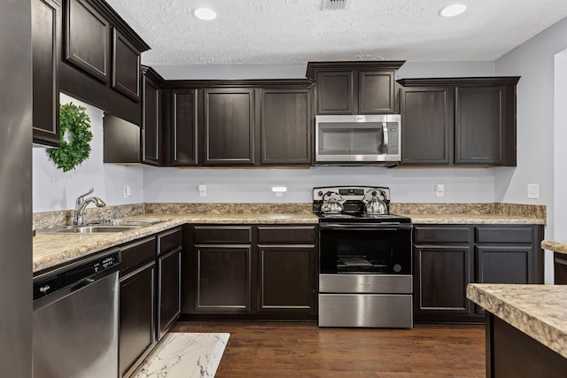 kitchen featuring appliances with stainless steel finishes, a sink, a textured ceiling, and light countertops