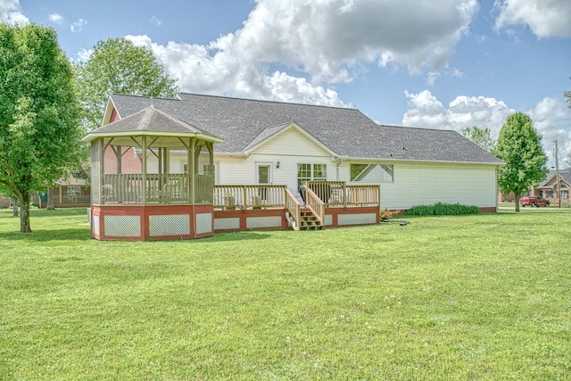 back of house featuring a wooden deck, a shingled roof, and a yard