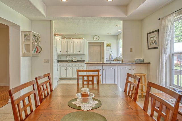dining area with recessed lighting, a textured ceiling, and a raised ceiling