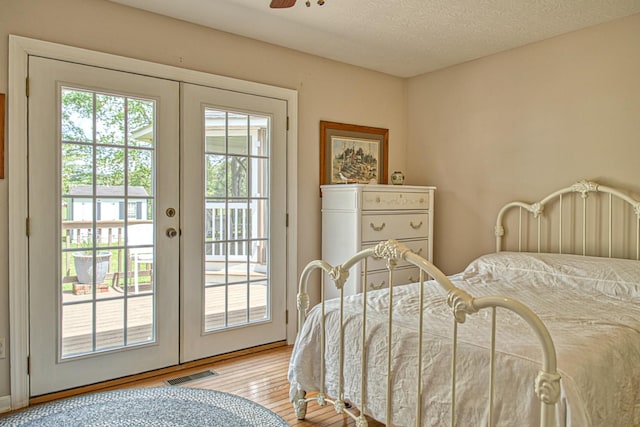 bedroom with visible vents, french doors, light wood-style flooring, access to outside, and ceiling fan