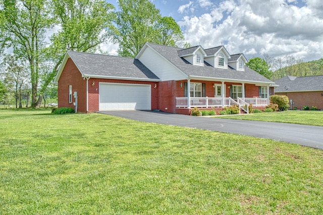 new england style home featuring driveway, a porch, brick siding, a front yard, and a garage