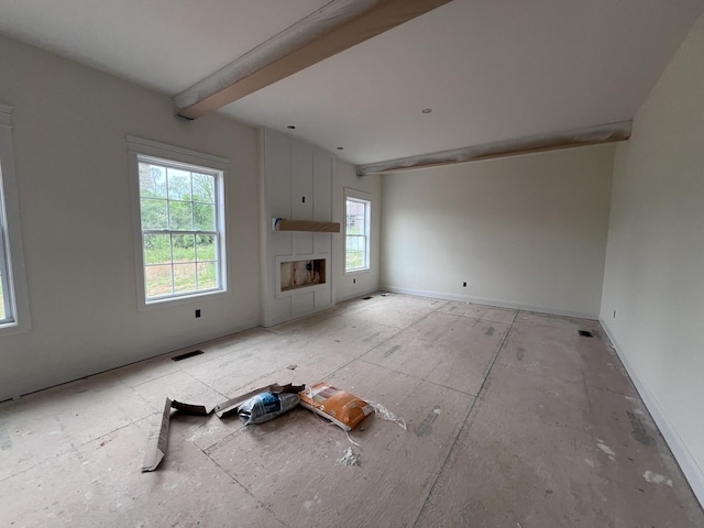 unfurnished living room featuring a large fireplace, baseboards, visible vents, and beam ceiling