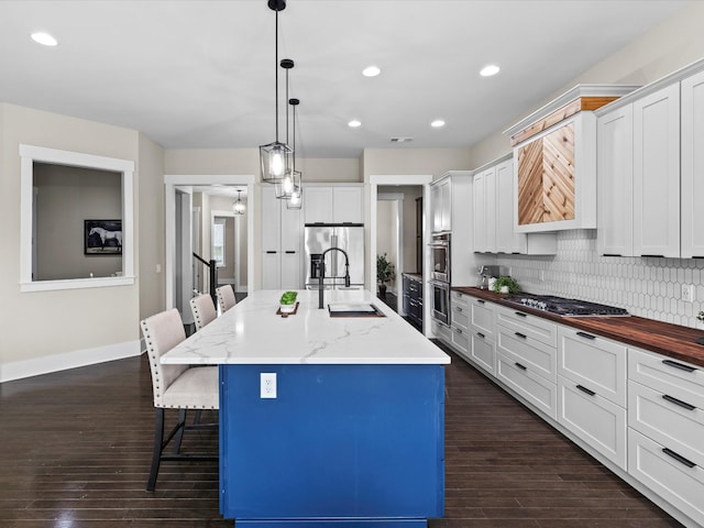 1068 Amelia Park Dr, Franklin, TN 37067 - kitchen featuring stainless steel appliances, a kitchen breakfast bar, a sink, dark wood finished floors, and decorative backsplash