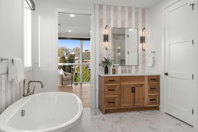 full bathroom featuring recessed lighting, marble finish floor, a freestanding tub, and vanity