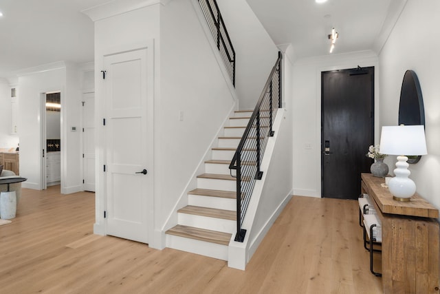 stairway with crown molding, wood finished floors, and baseboards