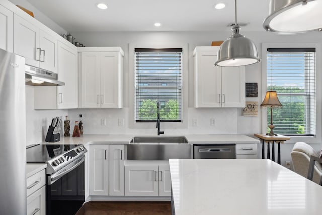 kitchen featuring a sink, stainless steel appliances, light countertops, under cabinet range hood, and recessed lighting