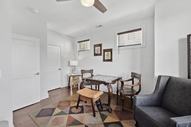 living area featuring a ceiling fan, visible vents, wood finished floors, and baseboards