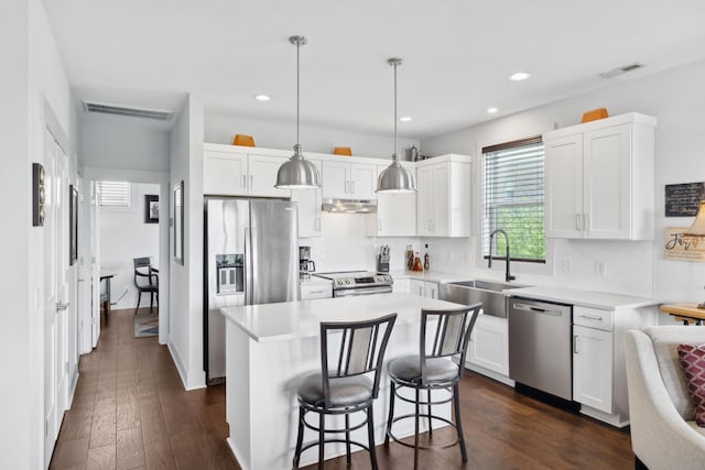 kitchen with tasteful backsplash, stainless steel appliances, under cabinet range hood, a sink, and visible vents