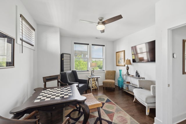 living area featuring dark wood finished floors, baseboards, and a ceiling fan