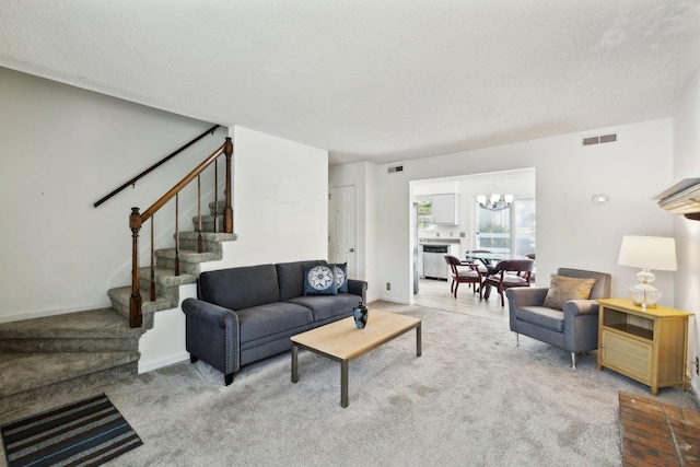 carpeted living area with visible vents, stairs, baseboards, and an inviting chandelier