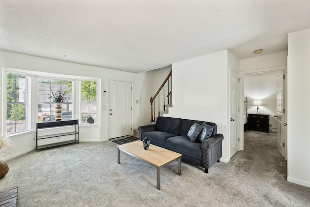 carpeted living room featuring stairway, baseboards, and a textured ceiling