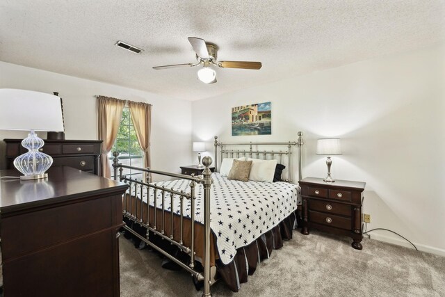 carpeted bedroom featuring a ceiling fan, a textured ceiling, and visible vents