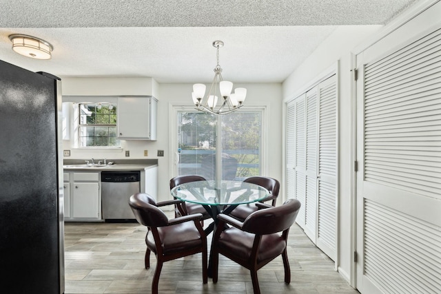 dining space with an inviting chandelier, a textured ceiling, and light wood-style floors