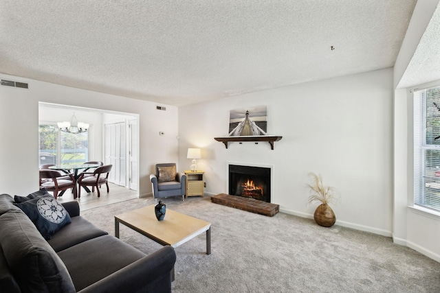 carpeted living room featuring a textured ceiling, a fireplace, a chandelier, and visible vents