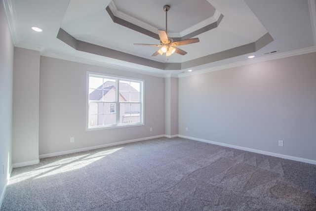carpeted empty room featuring a raised ceiling, ornamental molding, a ceiling fan, and visible vents