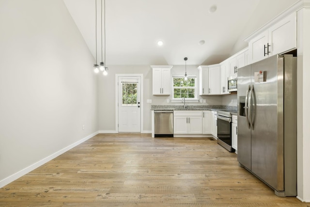 kitchen featuring stainless steel appliances, white cabinets, and vaulted ceiling