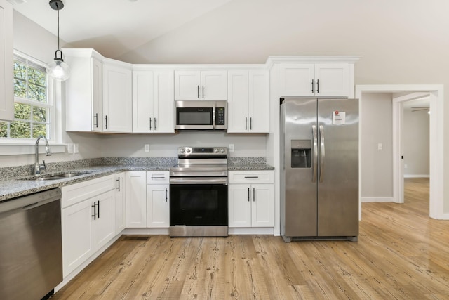kitchen featuring vaulted ceiling, a sink, white cabinetry, and stainless steel appliances