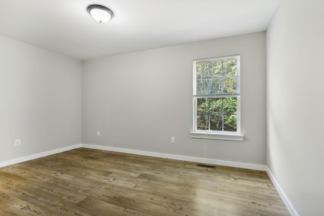 empty room with visible vents, wood finished floors, and baseboards