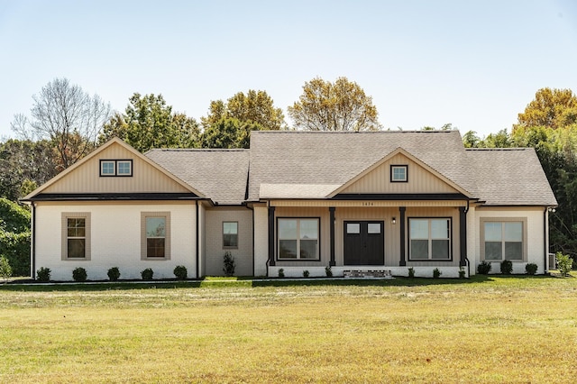 view of front of house with brick siding, a porch, a shingled roof, and a front yard
