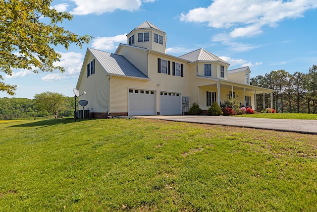 traditional-style house with a front lawn, metal roof, covered porch, driveway, and an attached garage