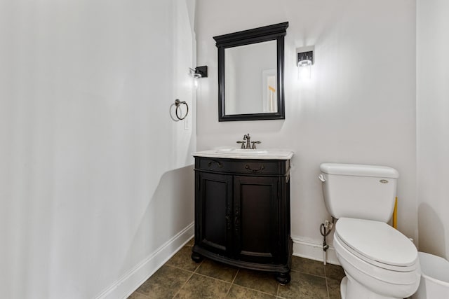 half bath with toilet, tile patterned flooring, vanity, and baseboards
