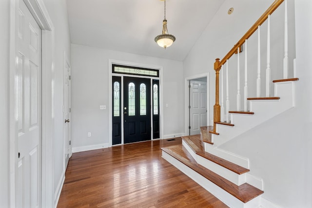 foyer entrance featuring stairs, hardwood / wood-style floors, vaulted ceiling, and baseboards