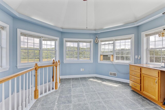 unfurnished sunroom featuring cooling unit, visible vents, a sink, and plenty of natural light