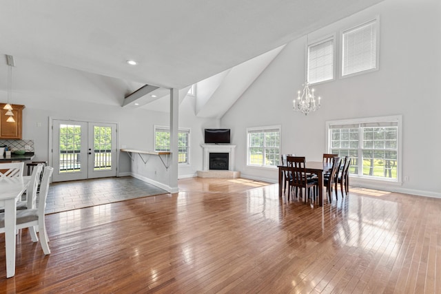 dining space featuring baseboards, high vaulted ceiling, an inviting chandelier, and french doors