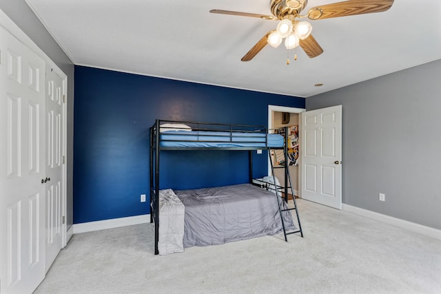 bedroom with baseboards, ceiling fan, a closet, and carpet flooring