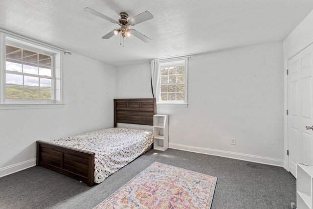 bedroom featuring a textured ceiling, a ceiling fan, dark colored carpet, and baseboards