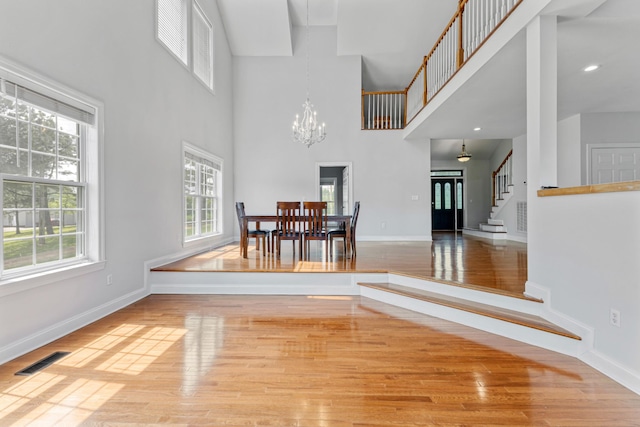 dining area featuring a notable chandelier, stairs, visible vents, baseboards, and wood finished floors