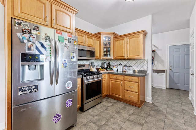 kitchen with tasteful backsplash, glass insert cabinets, appliances with stainless steel finishes, dark countertops, and baseboards