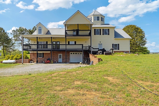 rear view of house with driveway, a balcony, an attached garage, a lawn, and a ceiling fan