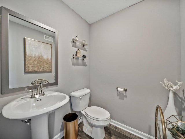 bathroom featuring toilet, a sink, wood finished floors, and baseboards