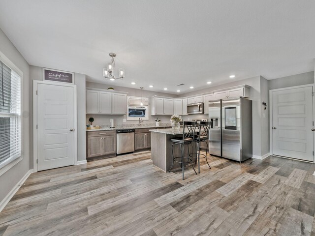 kitchen with recessed lighting, a chandelier, a breakfast bar, baseboards, and appliances with stainless steel finishes