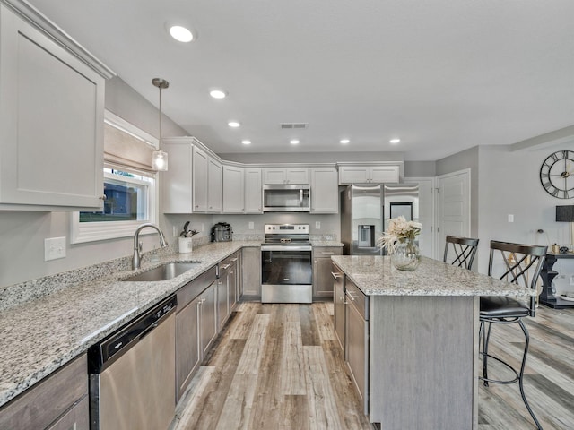 kitchen featuring visible vents, a breakfast bar area, appliances with stainless steel finishes, a sink, and light wood-type flooring