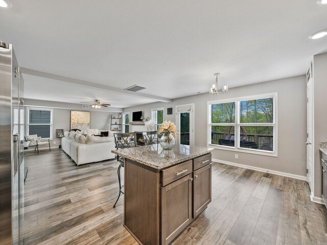 kitchen with visible vents, wood finished floors, open floor plan, and a kitchen breakfast bar