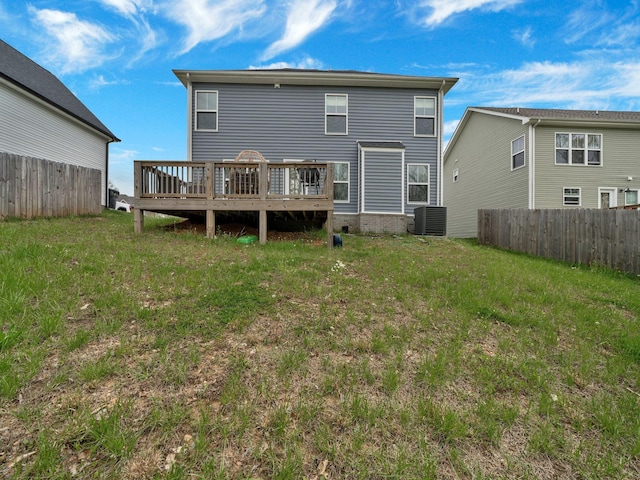 rear view of property featuring a deck, a lawn, central air condition unit, and fence